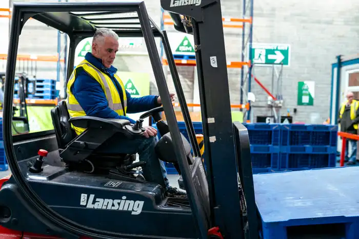A_man_wearing_a_safety_vest_operates_a_forklift_in_a_warehouse_setting _ISM Training_and_Recruitment