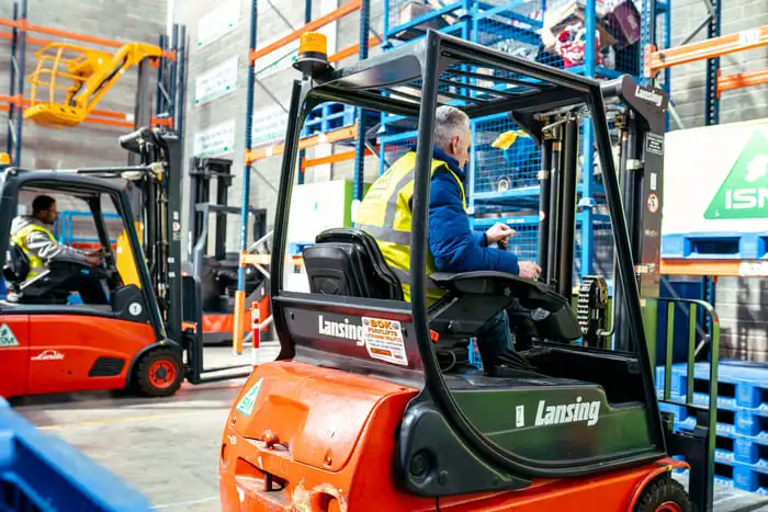 A_forklift_truck_in_a_warehouse_with_workers_inspecting_and_maintaining _ISM Training_and_Recruitment