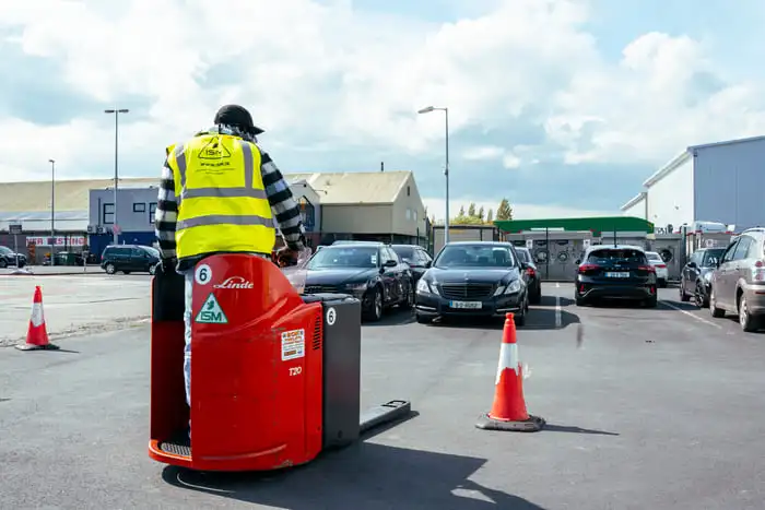 A_man_in_a_yellow_vest_stands_on_a_red_hand_truck _ISM Training_and_Recruitment