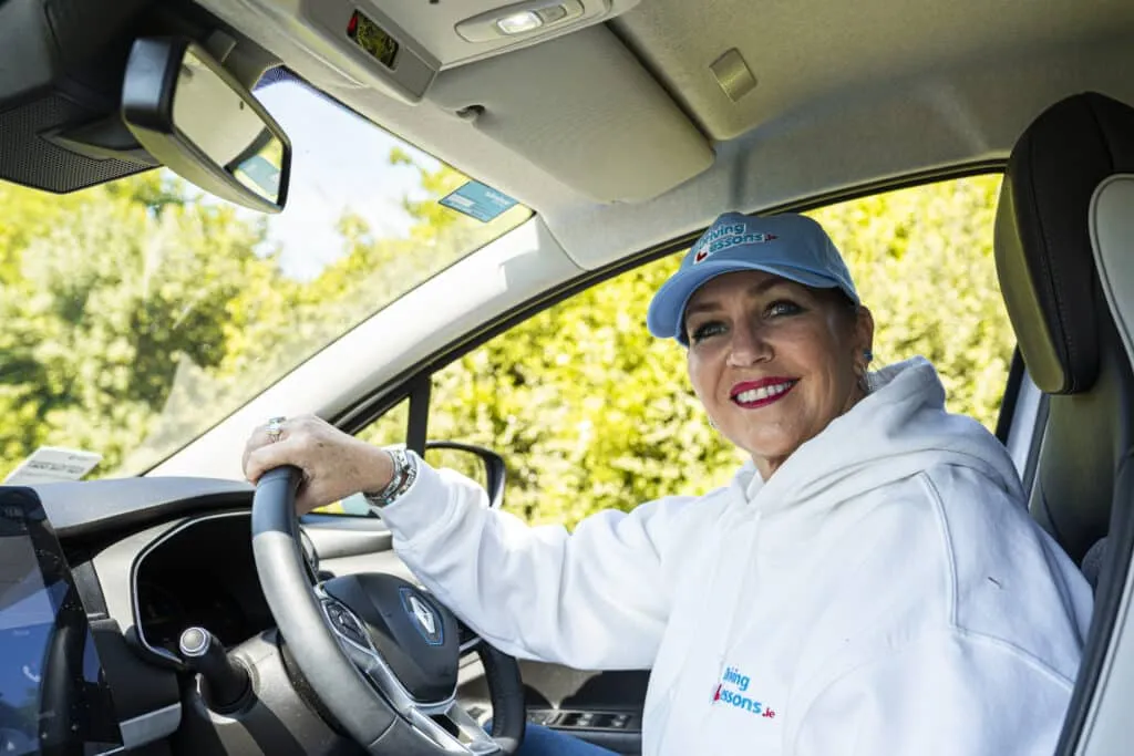 In_the_driver's_seat_of_a_car_woman_instructor_is_seated_ISM_Driving_Lessons