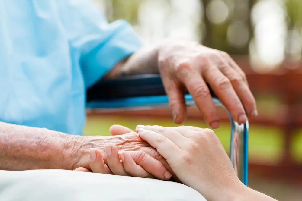 A_person_gently_holds_the_hand_of_an_elderly _ISM_Training_and_Recruitment
